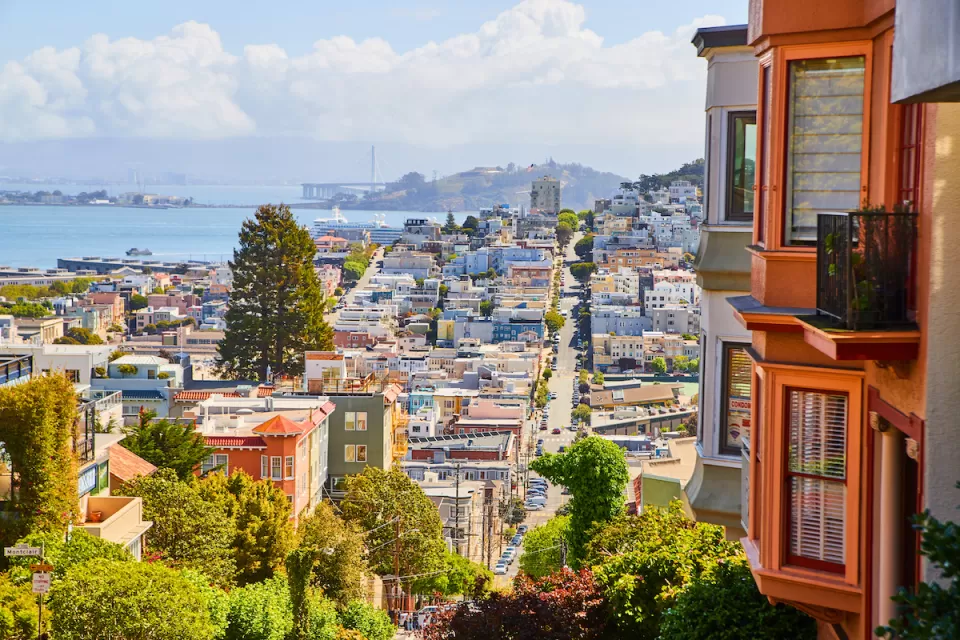 View of San Francisco from top of hill with Victorian houses in foreground.